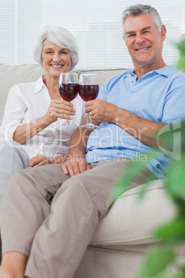 Husband and wife clinking their glasses of red wine