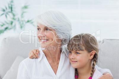 Cute girl and grandmother sitting on the couch