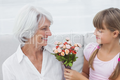 Cute girl giving a bunch of flowers to her grandmother