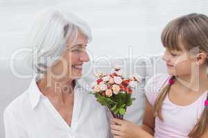 Cute girl giving a bunch of flowers to her grandmother