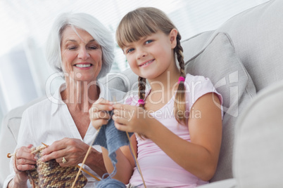 Young girl and her granddaughter knitting together