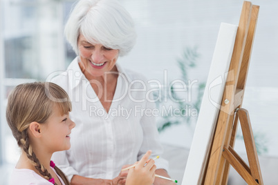 Grandmother and cute granddaughter painting together