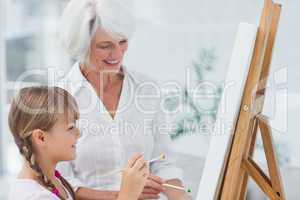 Cheerful grandmother and granddaughter painting together