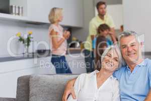 Elderly couple sitting on the couch and smiling at camera