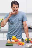 Attractive man eating a slice of bell pepper