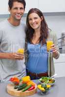Delighted couple holding glass of orange juice