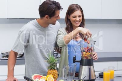 Couple putting fruits into blender