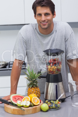 Man putting a strawberry in the blender
