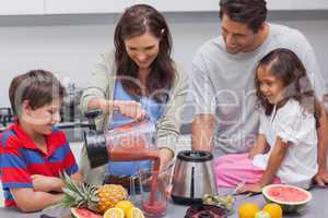 Woman with family pouring fruit from a blender