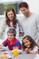 Parents looking at their children having breakfast