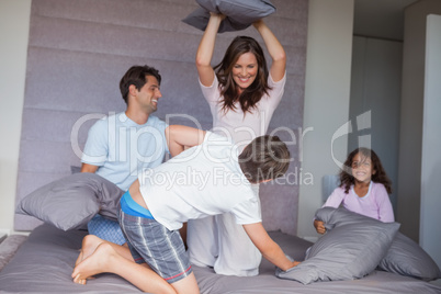 Family having a pillow fight on the bed