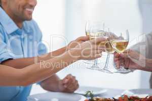 Close up of hands clinking glasses of white wine