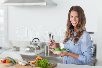 Woman in the kitchen holding a salad bowl with lettuce