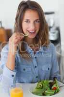 Pretty woman eating a salad with a glass of orange juice
