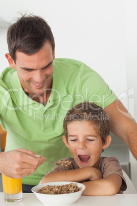 Father giving cereal to his son