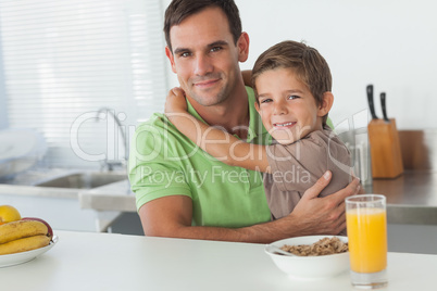 Son embracing his father while having breakfast