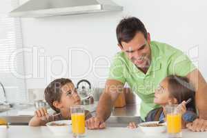 Father talking to his children while they are having breakfast