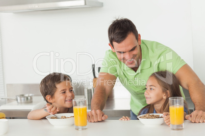 Father chatting to his children while they are having breakfast