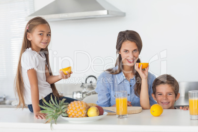 Siblings raising a half orange in the kitchen