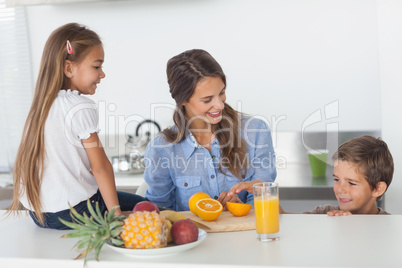 Attractive woman cutting an orange for her children