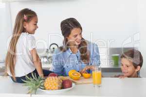 Attractive woman cutting an orange for her children