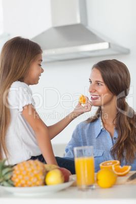 Young girl giving an orange segment to her mother