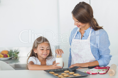 Little girl dunking a cookie into a glass of milk