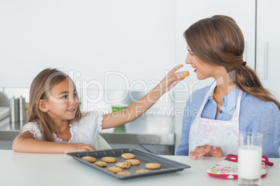 Little girl giving a cookie to her mother