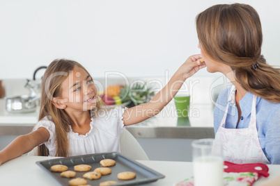 Young girl giving a cookie to her mother