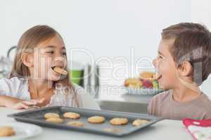Siblings with cookies in their mouth