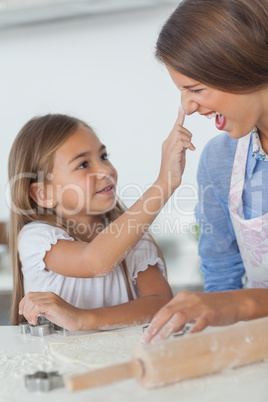 Little girl putting flour on the nose of her mother