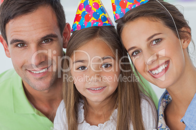 Parents and daughter wearing a party hat