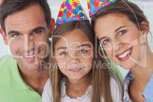 Parents and daughter wearing a party hat