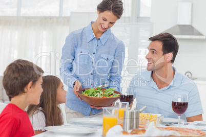 Pretty woman bringing a salad to her family