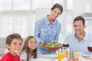 Portrait of a woman bringing a salad to her family