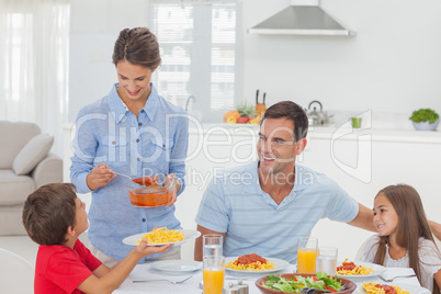 Woman giving pasta sauce to her son