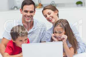 Cheerful parents and children using a laptop