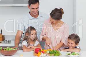 Children looking at their mother who is preparing vegetables