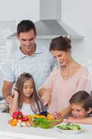 Woman cutting vegetables next to her children