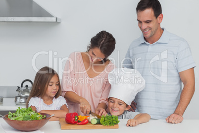 Children looking at their mother who is cutting vegetables