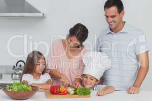 Children looking at their mother who is cutting vegetables