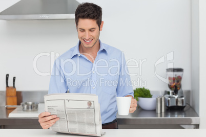Man reading a newspaper in the kitchen