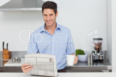 Man reading a newspaper and holding a cup of coffee