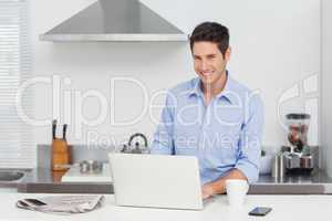 Portrait of a man using a laptop in the kitchen