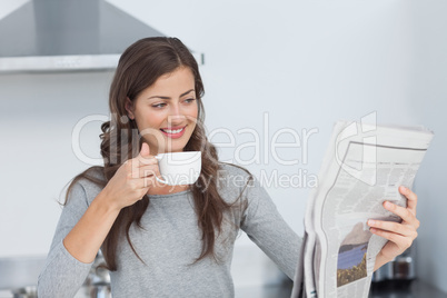 Woman with a cup of coffee reading a newspaper