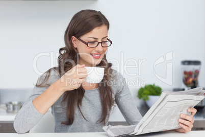 Woman holding a cup of coffee and reading a newspaper