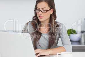 Woman typing on her laptop in the kitchen