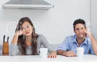 Tired couple sitting at the table with a cup of coffee