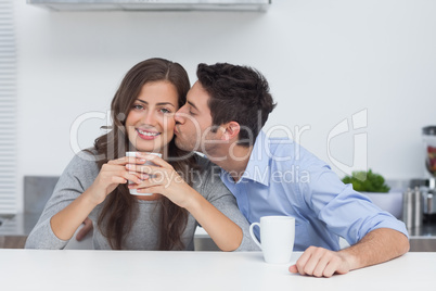 Man embracing wife who is holding a cup of coffee