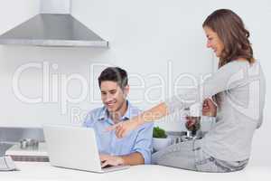 Wife pointing at the laptop of her husband